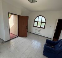 Zimmer in einer Hütte mit Terrassentüren, Fliesenboden und dunkelblauem Sessel.