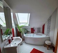 Badezimmer in einem Einfamilienhaus mit Badewanne und Dachfenster, rot-weiße Fliesen.
