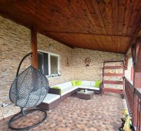 Die Terrasse des Einfamilienhauses in Klokočov mit einem Hängesessel und Korbmöbeln.