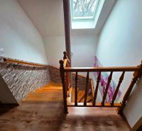 Eine Treppe mit Holzdekor, einer Blumen-Tapete und einem Dachfenster in einem Einfamilienhaus.