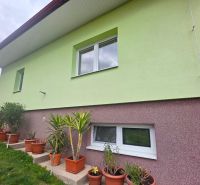 Die Fassade des Einfamilienhauses in Klokočov mit Blumenkästen und gepflegtem Grün im Hof.
