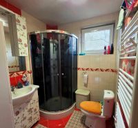 Badezimmer in einem Einfamilienhaus mit Toilette, Duschkabine und dekorativen Fliesen.