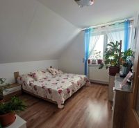 Schlafzimmer in einem Einfamilienhaus mit Holzboden und einem Bett mit einer Blumenüberdecke.