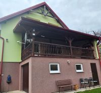 Ein Einfamilienhaus in Klokočov mit überdachter Terrasse, Grünflächen und Gartenmöbeln.