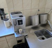 Küchenecke mit Kaffeemaschine, Edelstahlspüle und Utensilien in Gastronomiebereichen.