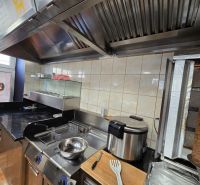 Küchenausstattung in Gastronomiebereichen mit Grill und Fritteuse zur Zubereitung von Speisen.