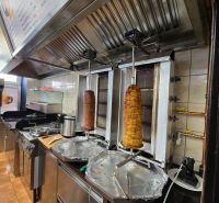 Eine Küche in einem Gastronomiebereich mit Ausstattung zur Zubereitung von Kebab, einschließlich Dunstabzugshaube.
