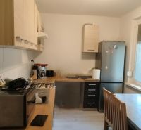 Küche in einer 2-Zimmer-Wohnung mit Geräten, Esstisch und großen Fenstern.