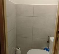 Badezimmer mit Toilette und Fliesen in einer 2-Zimmer-Wohnung.