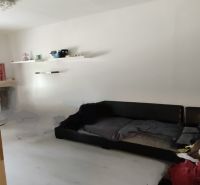 Wohnzimmer in einer 2-Zimmer-Wohnung mit weißen Wänden und einem schwarzen Sofa.