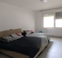 Schlafzimmer in einer 2-Zimmer-Wohnung mit großem Fenster und Bett.
