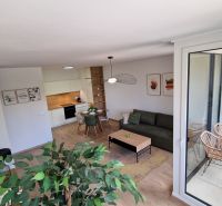 Innenraum einer 2-Zimmer-Wohnung mit Holzboden, modernen Möbeln und Balkon.