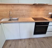 Küche mit Arbeitsplatte in Holzdekor und eingebauten Geräten in einer 2-Zimmer-Wohnung.