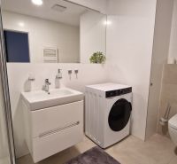 Badezimmer in einer 2-Zimmer-Wohnung mit Waschmaschine, Dusche und Waschbecken.