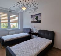 Schlafzimmer in einer 2-Zimmer-Wohnung mit zwei Betten und einem Boden in Holzoptik.