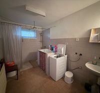 Badezimmer mit Waschbecken, Waschmaschine und Dusche in einem Einfamilienhaus.