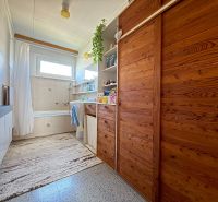 Badezimmer mit Holzschränken und Badewanne in einem Einfamilienhaus.