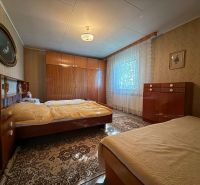 Schlafzimmer in einem Einfamilienhaus mit klassischen Möbeln, Boden mit Holzdekor, Vorhänge an den Fenstern.