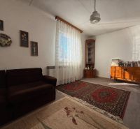 Wohnzimmer in einem Einfamilienhaus mit Teppichen, Sofa und Holzmöbeln.