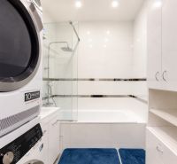 Badezimmer in einer 3-Zimmer-Wohnung mit Badewanne, Waschmaschine und weißen Möbeln.