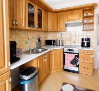 Küche in einer 3-Zimmer-Wohnung mit Holzschränken und einem Boden in Holzoptik.