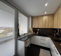 Küche in einer 3-Zimmer-Wohnung mit Holzboden, weißen Jalousien und Ausblick.
