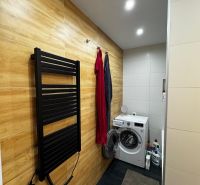 Badezimmer mit Waschmaschine, Boden mit Holzdekor, Handtuchhalter in einer 3-Zimmer-Wohnung.