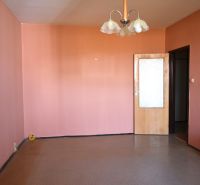 Ein Zimmer mit rosa Wänden und braunem Boden in einer 3-Zimmer-Wohnung.