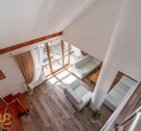 Wohnzimmer mit Holzboden, Treppe und großen Fenstern in einer Vierzimmerwohnung.