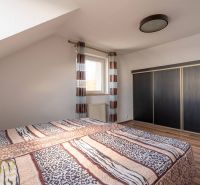 Schlafzimmer in einer 4-Zimmer-Wohnung mit Bett, großem Schrank und Boden in Holzoptik.