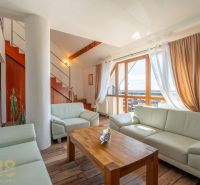 Wohnzimmer mit heller Couch, Treppe und Holzboden in einer 4-Zimmer-Wohnung.