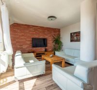 Wohnzimmer in einer 4-Zimmer-Wohnung mit Ziegelwand und Holzboden.