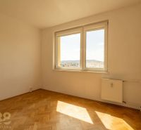 Ein Zimmer mit Fenster, Heizkörper und einem Boden mit Holzdekor in einer 4-Zimmer-Wohnung.