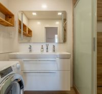 Badezimmer in einer 4-Zimmer-Wohnung, Waschbecken mit Spiegel, Waschmaschine, Boden mit Holzdekor.