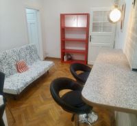 Wohnzimmer mit Bartresen, Sofa und Regalen in einer 2-Zimmer-Wohnung mit Holzboden.