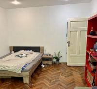 Schlafzimmer in einer 2-Zimmer-Wohnung mit Bett, rotem Regal und Boden in Holzoptik.