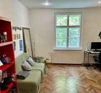 Wohnzimmer in einer 2-Zimmer-Wohnung mit Holzboden, Sofa und Computertisch.