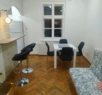 Wohnzimmer in einer 2-Zimmer-Wohnung mit Holzboden, Esstisch und Stühlen.