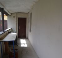 Ein Flur mit weißen Wänden, Risse im Boden, ein Tisch, Türen in einem Einfamilienhaus.