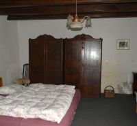 Schlafzimmer in einem Einfamilienhaus mit Bett, Schrank und Stühlen.