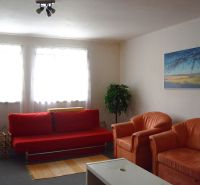 Wohnzimmer eines Einfamilienhauses mit rotem Sofa und orangefarbenen Sesseln.