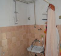 Badezimmer mit Fliesen und Vorhang in einem Einfamilienhaus, einfaches Waschbecken.