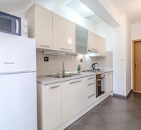 Helle Küche im Ferienapartment mit Einbaugeräten und Fliesenboden.