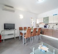 Helle Küche mit Esstisch und Fernseher in einer Ferienwohnung.