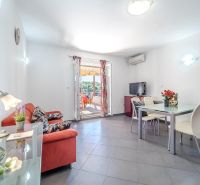 Helles Wohnzimmer mit Sofa, Esstisch und Terrasse in der Ferienwohnung.