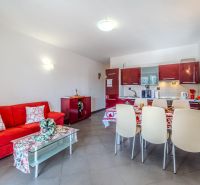 Ferienwohnung mit rotem Sofa und Küche mit Essecke.