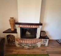 Kamin in einer Ferienwohnung mit dekorativem Stein und Boden in Holzoptik.