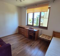 Ein Zimmer in einem Ferienapartment mit Sofa, Bett, Schreibtisch und Holzboden.