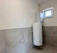 Ein Badezimmer in einem Einfamilienhaus mit Fliesen an den Wänden und einem Boiler.