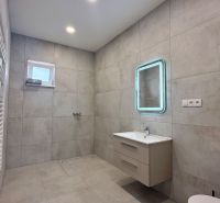 Badezimmer in einem Einfamilienhaus mit modernem Waschbecken, Spiegel und Handtuchheizkörper.